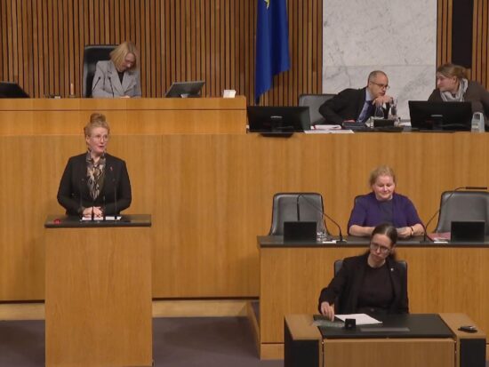 Fiona Fiedler hält eine Rede im österreichischen Nationalratssaal, Corinna Schumann sitz als Sozialministerin auf der Regierungsbank.